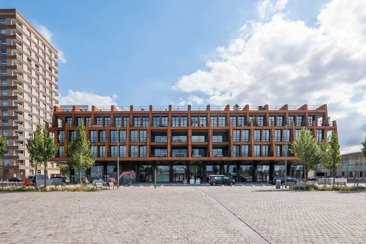 Modern apartment building with a rust-coloured steel facade on a paved square in Antwerp
