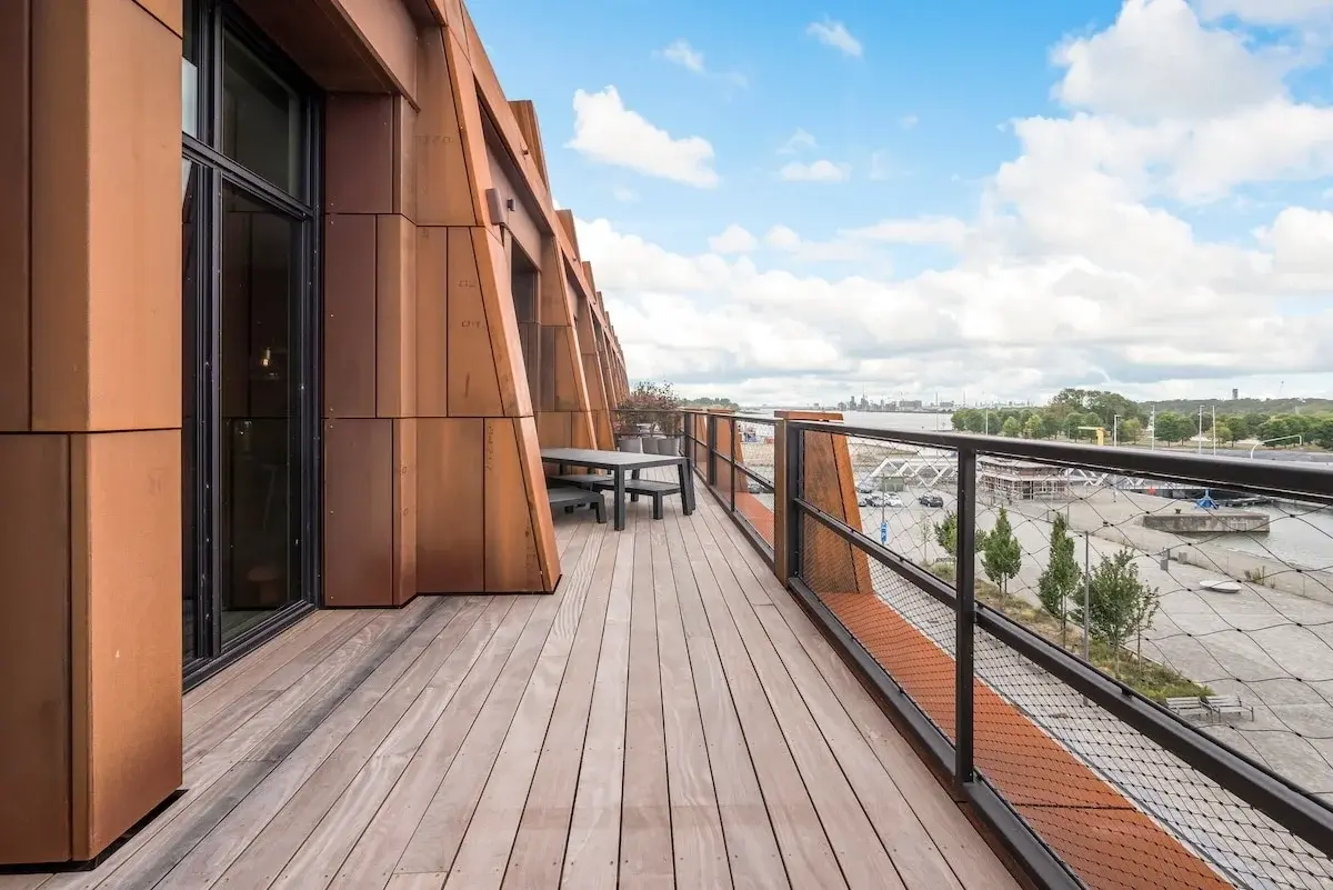 Modern apartment building with a rust-coloured steel facade on a paved square in Antwerp